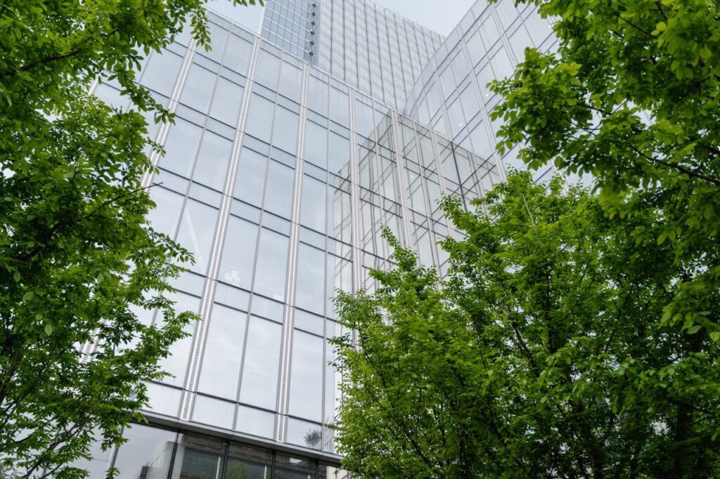 Building facade with glass windows and green trees at the ends