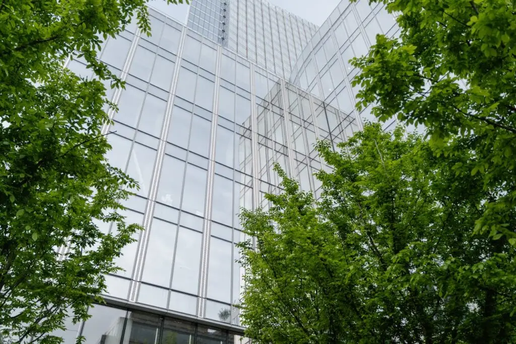 Fachada de edificio con cristaleras y arboles verdes en los extremos